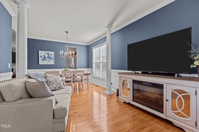 living room with crown molding, a wainscoted wall, ornate columns, and light wood-type flooring