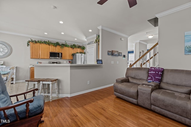 living area with light wood-type flooring, baseboards, ornamental molding, and a ceiling fan