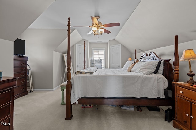 bedroom with baseboards, lofted ceiling, ceiling fan, light colored carpet, and two closets