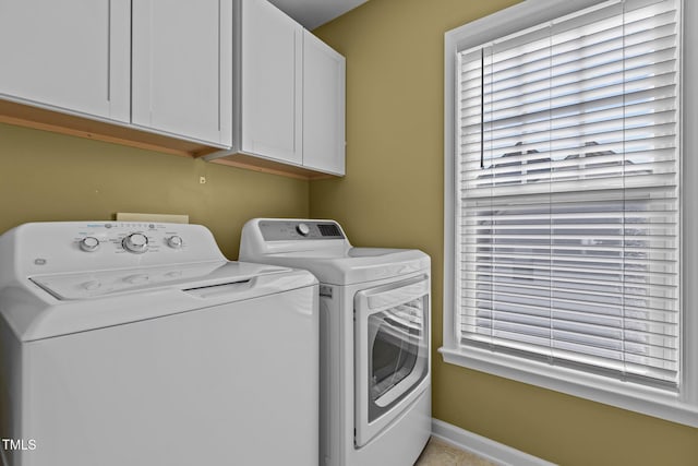 laundry area with cabinet space, washing machine and dryer, baseboards, and a healthy amount of sunlight