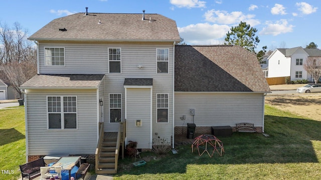 rear view of house featuring a shingled roof and a yard