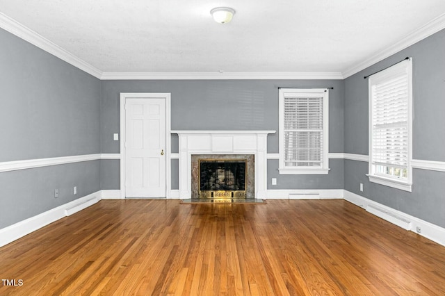 unfurnished living room with wood finished floors, baseboards, visible vents, a high end fireplace, and crown molding