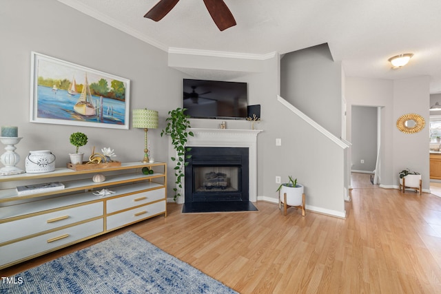 living area featuring a fireplace with flush hearth, wood finished floors, baseboards, and ceiling fan