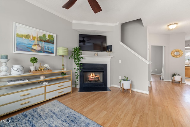 living room featuring a fireplace with flush hearth, baseboards, a ceiling fan, and wood finished floors