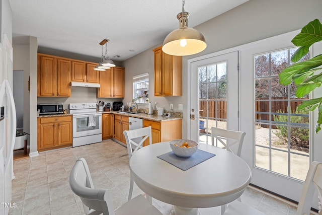 kitchen featuring under cabinet range hood, decorative light fixtures, white appliances, and light stone countertops