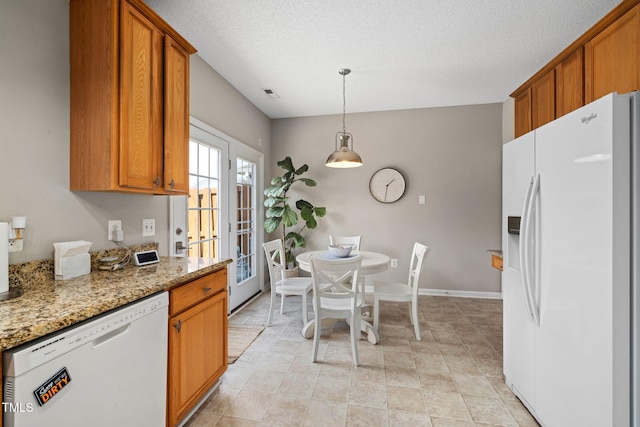 kitchen featuring baseboards, light stone countertops, brown cabinets, white appliances, and a textured ceiling