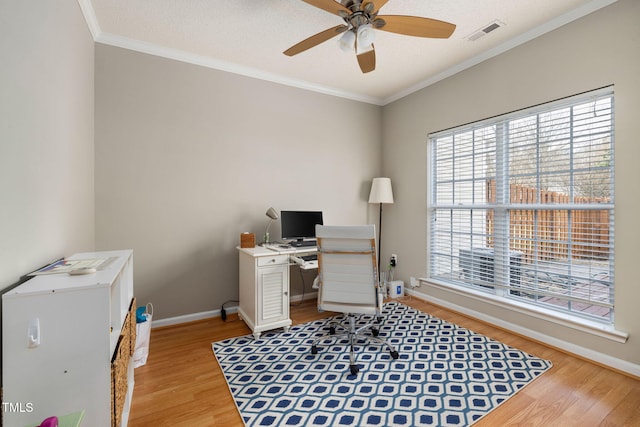 office space with light wood finished floors, visible vents, crown molding, baseboards, and a ceiling fan