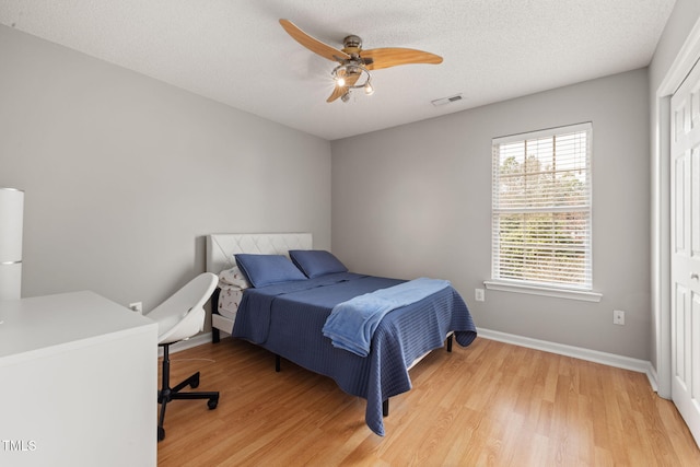 bedroom featuring visible vents, a textured ceiling, light wood-type flooring, and baseboards