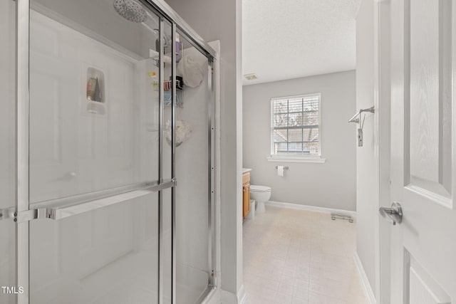 bathroom featuring baseboards, toilet, a stall shower, and a textured ceiling