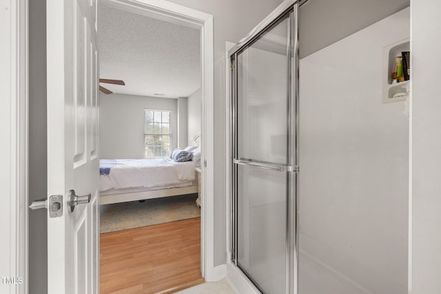 ensuite bathroom featuring connected bathroom, a textured ceiling, and a shower stall