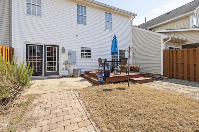 rear view of house with a wooden deck, a patio area, and fence