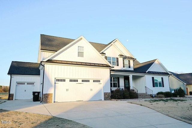 view of front of house featuring board and batten siding, metal roof, driveway, an attached garage, and a standing seam roof