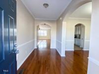 corridor featuring wood finished floors, arched walkways, and ornamental molding