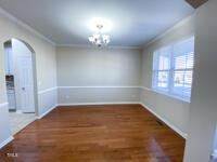 unfurnished dining area with wood finished floors, baseboards, arched walkways, ornamental molding, and a chandelier