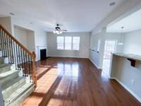 unfurnished living room with wood finished floors, a fireplace, baseboards, ceiling fan, and stairs