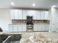 kitchen featuring tasteful backsplash, recessed lighting, stainless steel appliances, white cabinetry, and a sink