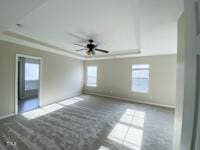 unfurnished room with a tray ceiling, baseboards, ceiling fan, and ornamental molding