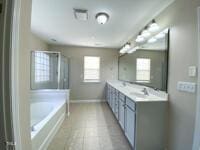 bathroom featuring double vanity, baseboards, and a bath