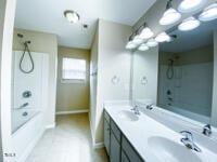 bathroom with shower / bathing tub combination, double vanity, baseboards, and a sink