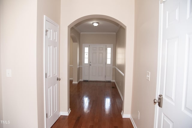 corridor featuring baseboards, arched walkways, and dark wood-type flooring