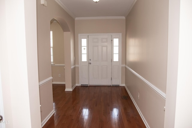 foyer entrance with visible vents, baseboards, arched walkways, ornamental molding, and wood-type flooring