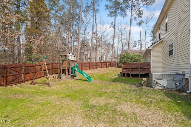 view of yard featuring a deck, a playground, a fenced backyard, and central AC