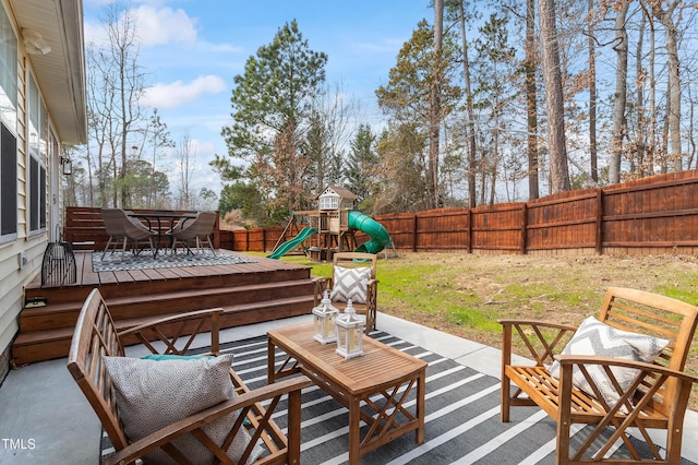 view of patio / terrace with outdoor dining space, a playground, and a fenced backyard