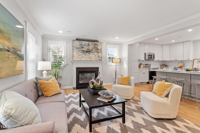 living area featuring a glass covered fireplace, light wood-style flooring, recessed lighting, and ornamental molding