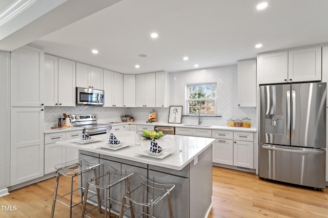 kitchen featuring a kitchen breakfast bar, light wood-type flooring, appliances with stainless steel finishes, and a sink