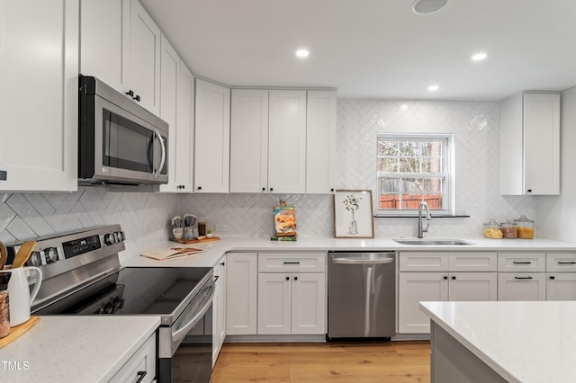 kitchen featuring white cabinetry, stainless steel appliances, light wood-type flooring, and a sink