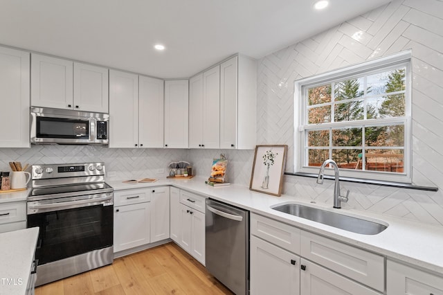 kitchen with white cabinets, appliances with stainless steel finishes, light countertops, and a sink