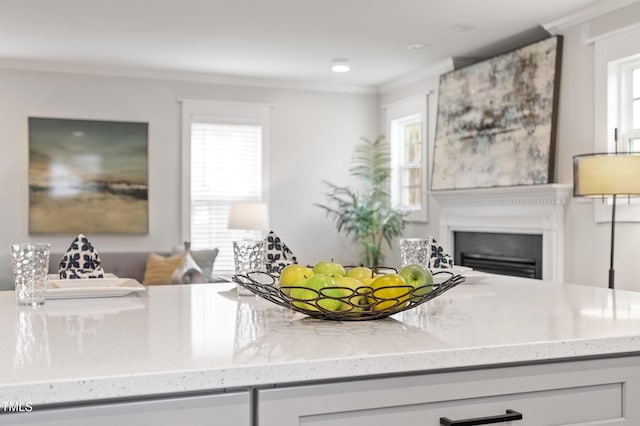 kitchen with light stone counters, a glass covered fireplace, and ornamental molding