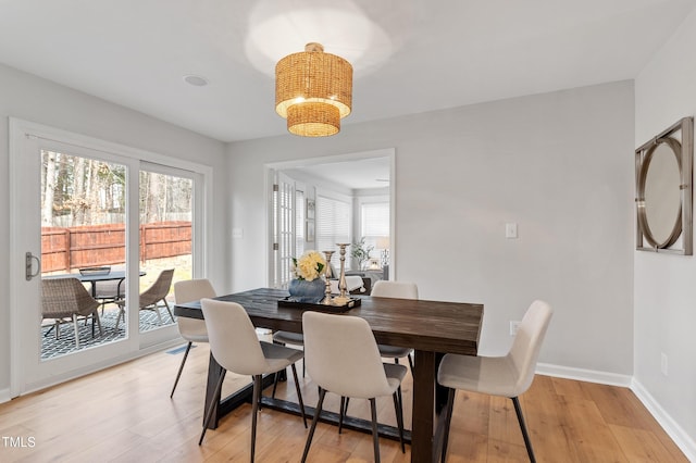 dining space featuring baseboards, light wood-style floors, and an inviting chandelier