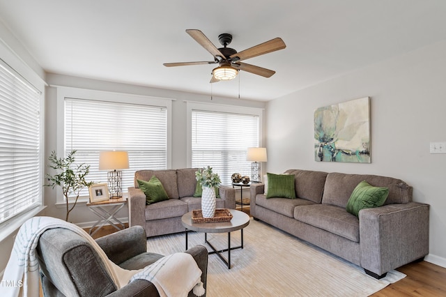 living room featuring baseboards, a ceiling fan, and light wood finished floors