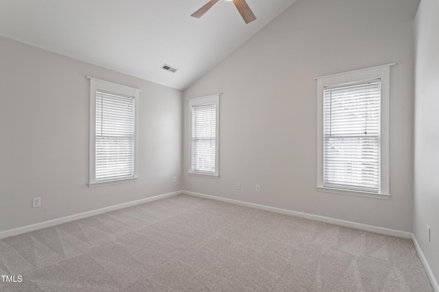 spare room featuring visible vents, plenty of natural light, light colored carpet, and a ceiling fan