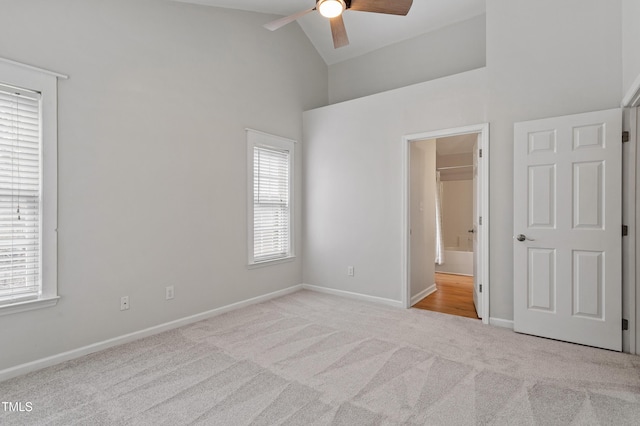 unfurnished bedroom with multiple windows, carpet flooring, baseboards, and high vaulted ceiling