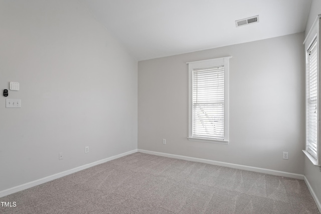 unfurnished room with visible vents, baseboards, carpet, and vaulted ceiling