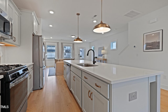 kitchen with a sink, light countertops, a center island with sink, and stainless steel appliances