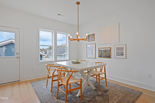 dining space with visible vents, baseboards, light wood-style floors, and an inviting chandelier