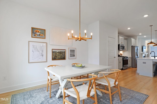 dining area with baseboards, recessed lighting, light wood-type flooring, and a chandelier