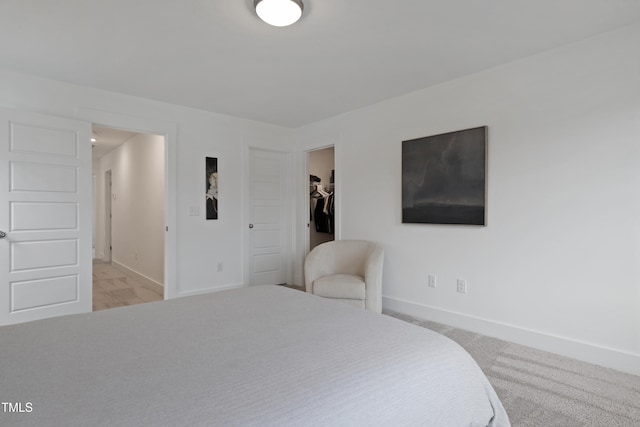 bedroom featuring a closet, baseboards, light colored carpet, and a spacious closet