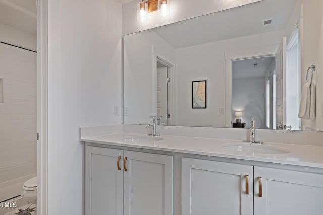 bathroom with a sink, visible vents, toilet, and double vanity