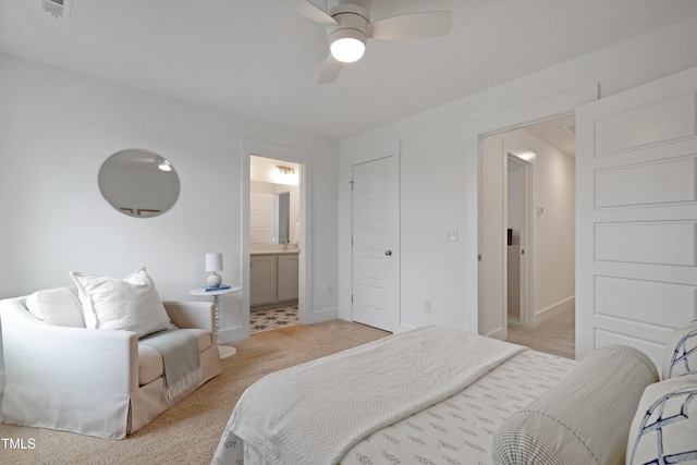bedroom featuring light colored carpet, ensuite bath, baseboards, and ceiling fan