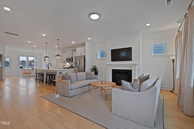 living room with recessed lighting, visible vents, a glass covered fireplace, and light wood finished floors