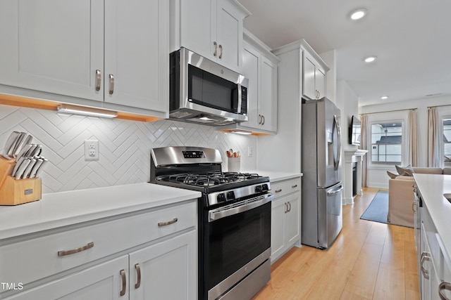 kitchen with backsplash, light wood-style flooring, stainless steel appliances, and light countertops