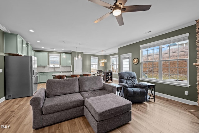 living room with visible vents, crown molding, light wood-type flooring, and baseboards