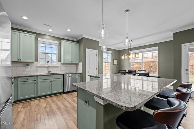 kitchen with visible vents, a sink, a center island, stainless steel appliances, and green cabinets