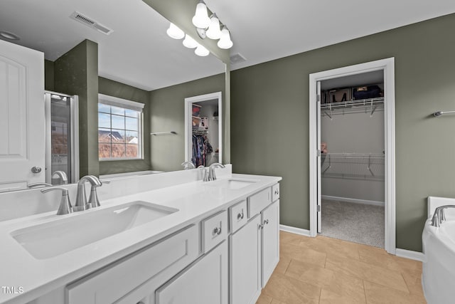 bathroom featuring double vanity, visible vents, a shower stall, and a sink