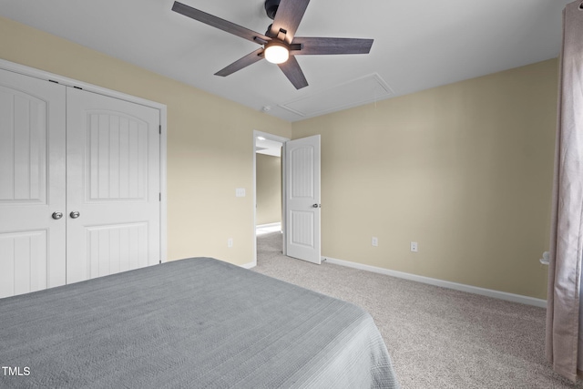 unfurnished bedroom with ceiling fan, baseboards, attic access, carpet floors, and a closet