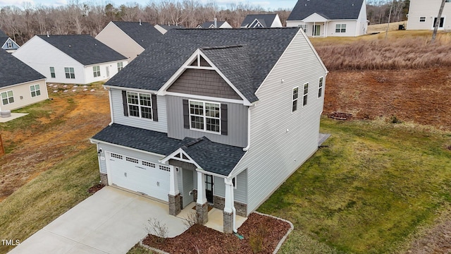 traditional-style home with driveway, a shingled roof, a front lawn, a garage, and stone siding